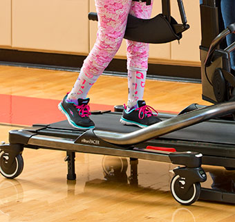 A close up of the legs of a young girl with cerebral palsy as she practices bwstt in the dynamic Pacer gait trainer.