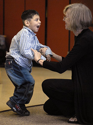 Linda Bidabe, founder of MOVE international smiles as she holds hands with a young boy with disabilities learning to walk. 