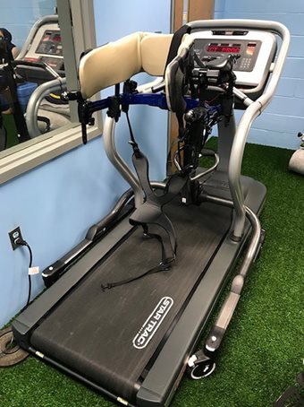 A Rifton gait trainer with a treadmill stability base is used on a treadmill.