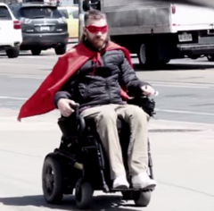 Ramp Man image - red cape blowing in the wind behind his wheelchair.
