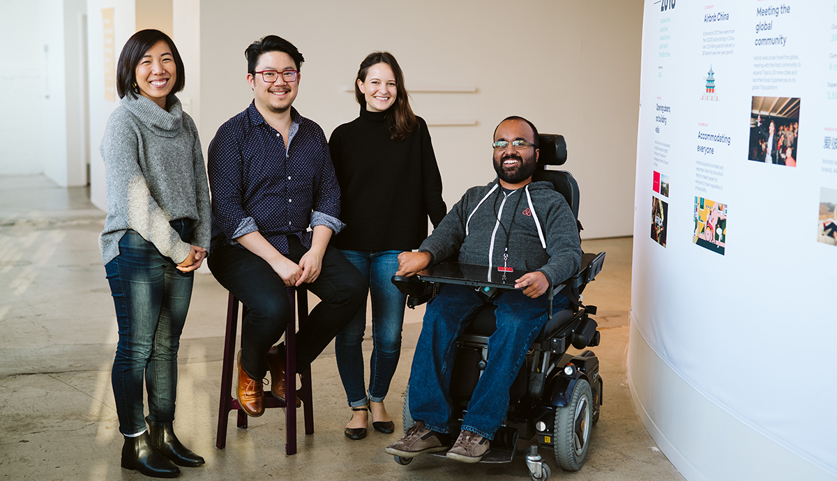 Nanako Era, Cameron Wu, Lydia Marouf and Madipalli (left to right) pose in front of a commemoration of Airbnb’s acquisition of Accomable on a timeline of the company’s history.