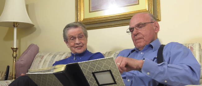 a woman who has alzheimer's sitting with her husband going through a photo album.