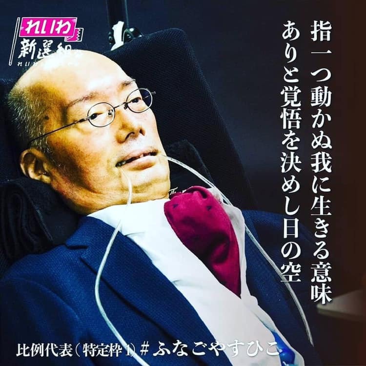 Shows Yasuhiko Funago of Japan, a disabled lawmaker recently elected to the upper parliament. He's wearing a blue suit and red kerchief, with breathing tubes going into his mouth.