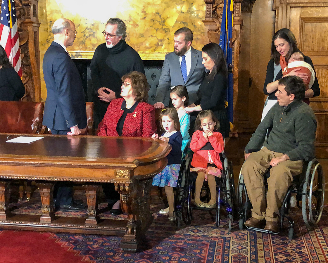 Pennsylvania Gov. Tom Wolf speaks with Matthew Rodreick and fellow advocates at the signing ceremony for the Spinal Cord Disability Research Grant Act.