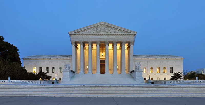 Supreme Court building, where the court recently allowed the public charge rule, shown at dusk, with light illuminating the front columns
