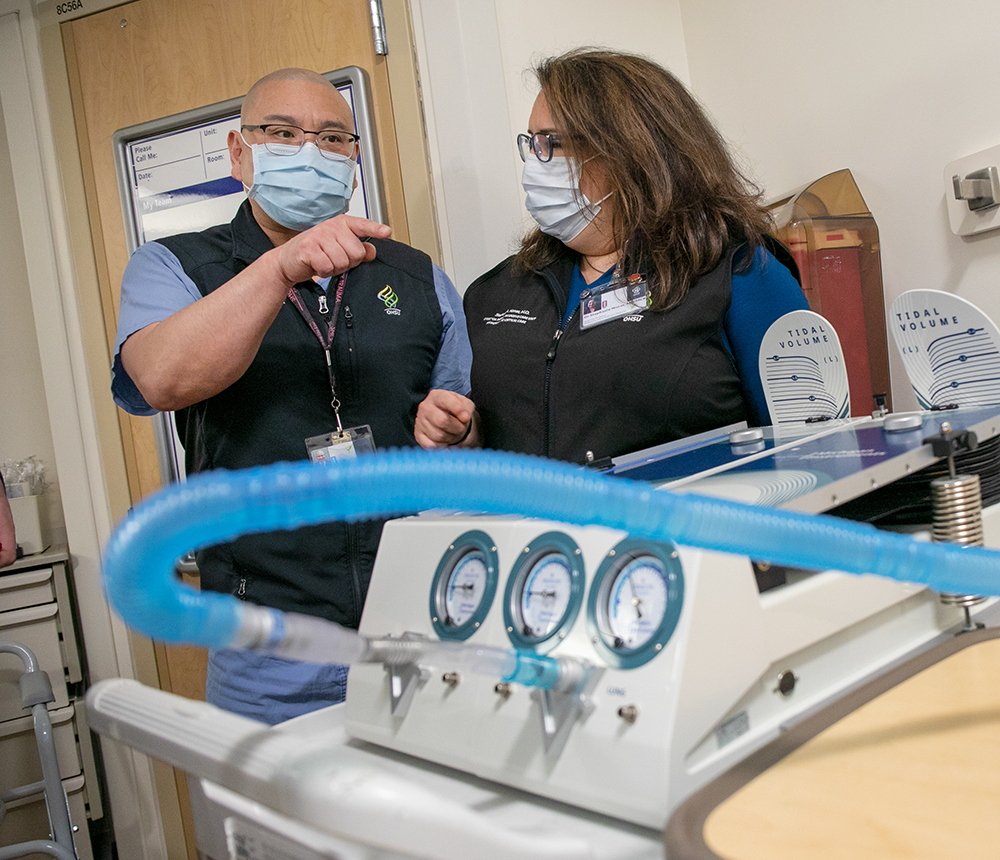 Drs. Albert Chi, left, and Stephanie Nonas discuss the ventilator performance in an endurance test at OHSU on April 22, 2020. The ventilator prototype is created with 3D-printing technology, and does not require electricity and operates off of a standard oxygen tank.