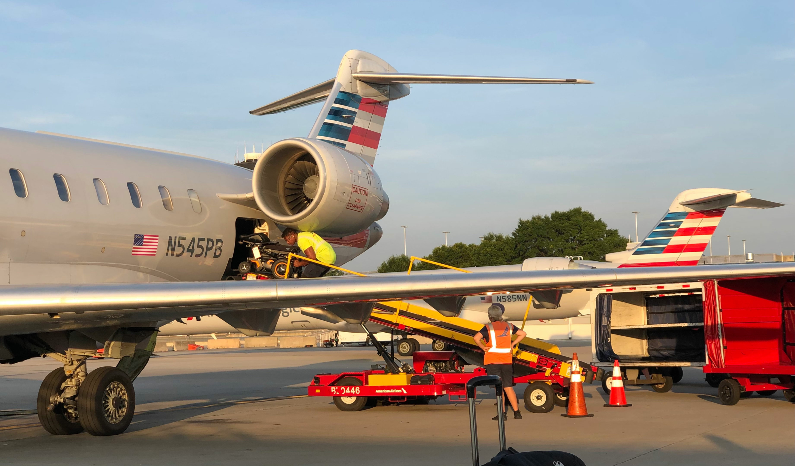 Image shows a power wheelchair going up the baggage ramp onto an American Airlines plane